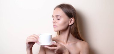 Genç bir kadın bir fincan kahvenin tadını çıkarıyor. Sabah çayı ile kadın portresi. Kopyalama alanı