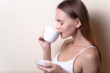 Genç bir kadın bir fincan kahvenin tadını çıkarıyor. Sabah çayı ile kadın portresi. Kopyalama alanı