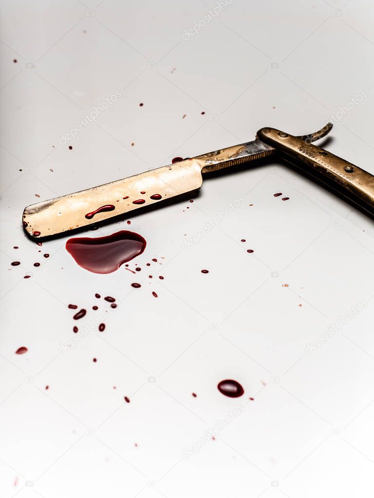 Dangerous razor bloodied on a light background. Razor with bloody smudges on the blade.