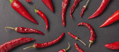 Siyah arka planda bir sürü kırmızı biber ve karabiber var. Yukarıdan görüntüle.