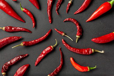 Siyah arka planda bir sürü kırmızı biber ve karabiber var. Yukarıdan görüntüle.