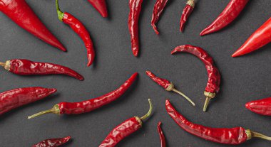 Siyah arka planda bir sürü kırmızı biber ve karabiber var. Yukarıdan görüntüle.