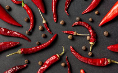 Siyah arka planda bir sürü kırmızı biber ve karabiber var. Yukarıdan görüntüle.
