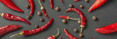 Siyah arka planda bir sürü kırmızı biber ve karabiber var. Yukarıdan görüntüle.