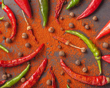 Bir sürü kırmızı, yeşil biber ve biber. Siyah arkaplana kırmızı biber serp, üst görünüm.