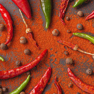 Bir sürü kırmızı, yeşil biber ve biber. Siyah arkaplana kırmızı biber serp, üst görünüm.