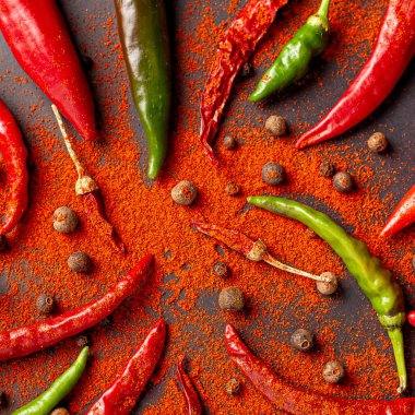 Bir sürü kırmızı, yeşil biber ve biber. Siyah arkaplana kırmızı biber serp, üst görünüm.