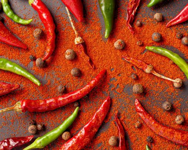 Bir sürü kırmızı, yeşil biber ve biber. Siyah arkaplana kırmızı biber serp, üst görünüm.