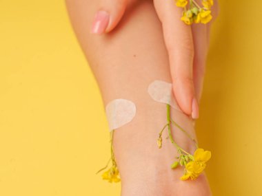 El sanatları, doğal kozmetik kadınları, sarı güzel kadınlar, bahar çiçekleri, parlak kontrast makyajlı eller, el bakımı. Moda, yaratıcı fotoğrafçı kız masada oturuyor, sarı zıt arkaplan. Yukarıdan bak, yakın plan..