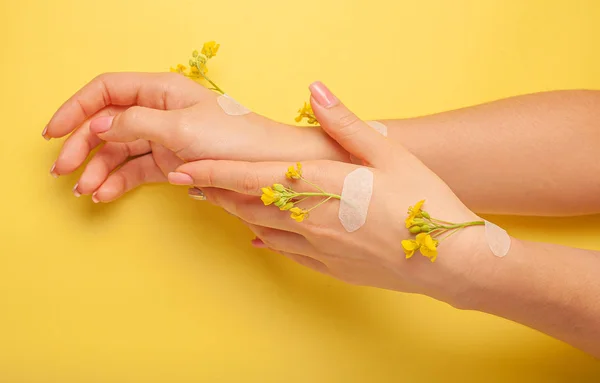 Hands art flower natural cosmetics women, yellow beautiful, spring flowers hand with bright contrast makeup, hand care. Fashion, creative beauty photo girl sitting at table,  yellow contrasting background.View from above, closeup.