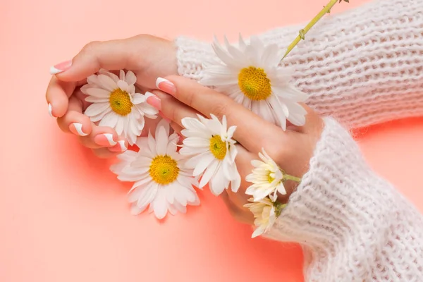 Slender young hands hold flowers, with a thin wrist, clean skin and French manicure. Flat lay photo, with place for text.