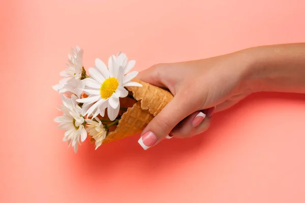 Slender young hands hold flowers, with a thin wrist, clean skin and French manicure. Flat lay photo, with place for text.