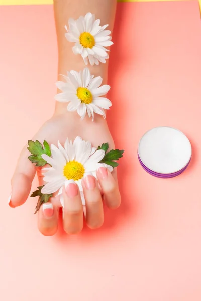 Mano Femenina Crema Cosmética Sobre Fondo Rosa Entre Flores Vista — Foto de Stock