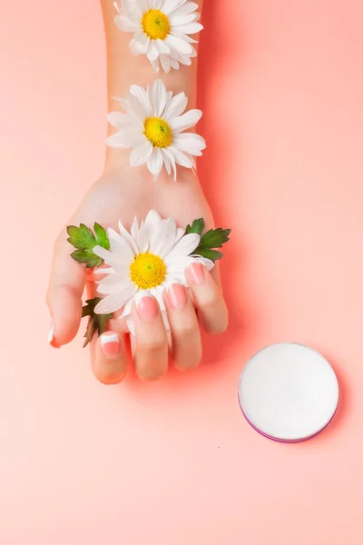 Mano Femenina Crema Cosmética Sobre Fondo Rosa Entre Flores Vista — Foto de Stock