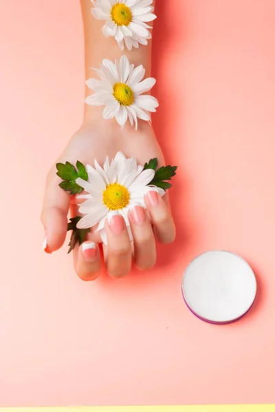 Mano Femenina Crema Cosmética Sobre Fondo Rosa Entre Flores Vista — Foto de Stock