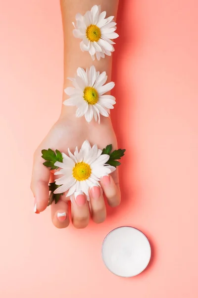 Mano Femenina Crema Cosmética Sobre Fondo Rosa Entre Flores Vista — Foto de Stock