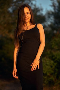 Yeşil sahil yakınında doğada güzel bir kız. Batan güneşin tadını çıkarıyor. Açık hava eğlencesi konsepti, parkta yürüyüş. Şehrin telaşından dolayı gevşeme.