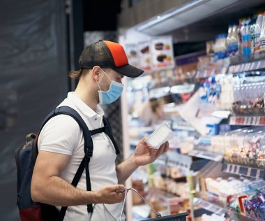 Tıp maskeli bir adam süpermarkette dolaşıyor. Halka açık yerlerde sağlık için kişisel koruyucu ekipman.