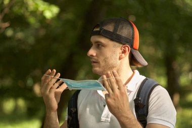 Adam maskesini suratından çıkardı. Parkta yürü..