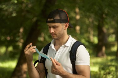 Adam maskesini suratından çıkardı. Parkta yürü..