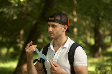 Adam maskesini suratından çıkardı. Parkta yürü..