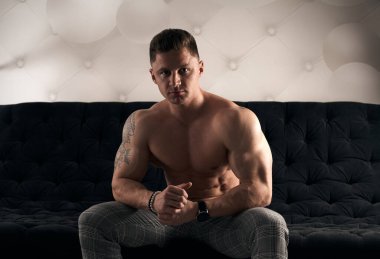 Kaslı adam odada oturuyor..