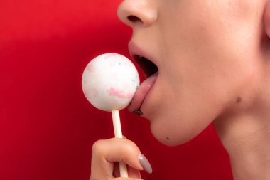 Kadın dudaklarını ve şekerlerini kapat. Çubukta şeker yiyen bir kız. Güzel dudaklar.