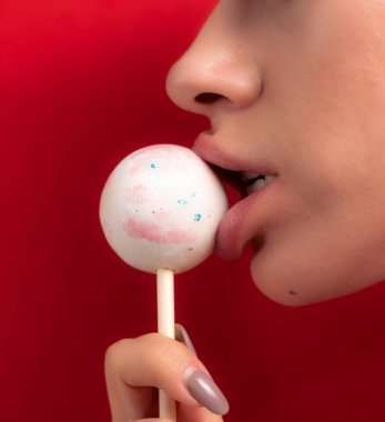 Kadın dudaklarını ve şekerlerini kapat. Çubukta şeker yiyen bir kız. Güzel dudaklar.