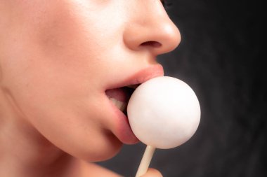 Kadın dudaklarını ve şekerlerini kapat. Çubukta şeker yiyen bir kız. Güzel dudaklar.