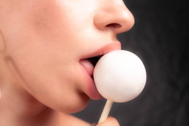 Kadın dudaklarını ve şekerlerini kapat. Çubukta şeker yiyen bir kız. Güzel dudaklar.