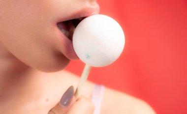 Kadın dudaklarını ve şekerlerini kapat. Çubukta şeker yiyen bir kız. Güzel dudaklar.