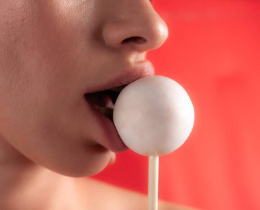 Kadın dudaklarını ve şekerlerini kapat. Çubukta şeker yiyen bir kız. Güzel dudaklar.