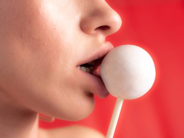 Kadın dudaklarını ve şekerlerini kapat. Çubukta şeker yiyen bir kız. Güzel dudaklar.