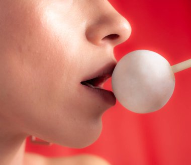 Kadın dudaklarını ve şekerlerini kapat. Çubukta şeker yiyen bir kız. Güzel dudaklar.