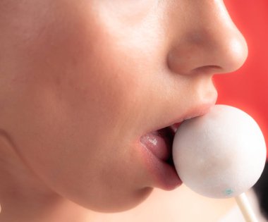Kadın dudaklarını ve şekerlerini kapat. Çubukta şeker yiyen bir kız. Güzel dudaklar.