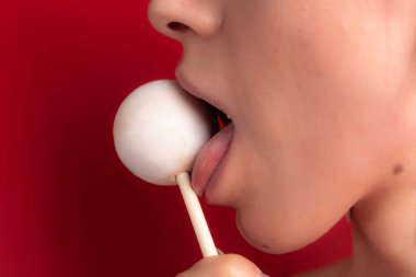 Kadın dudaklarını ve şekerlerini kapat. Çubukta şeker yiyen bir kız. Güzel dudaklar.