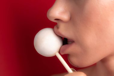 Kadın dudaklarını ve şekerlerini kapat. Çubukta şeker yiyen bir kız. Güzel dudaklar.