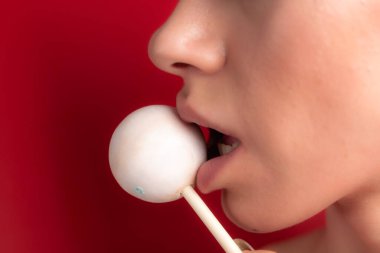 Kadın dudaklarını ve şekerlerini kapat. Çubukta şeker yiyen bir kız. Güzel dudaklar.