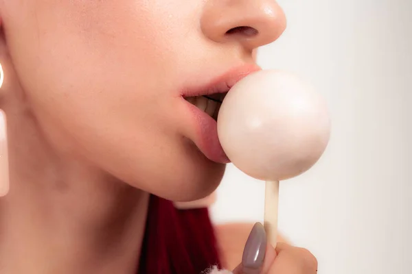 Close up of female lips and candy. Girl eating candy on a stick. Beautiful lips.