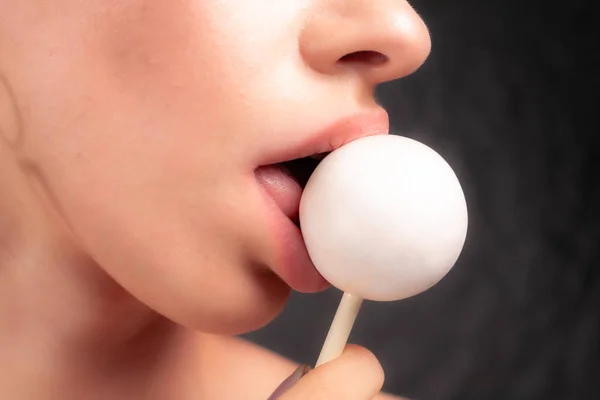 Close up of female lips and candy. Girl eating candy on a stick. Beautiful lips.