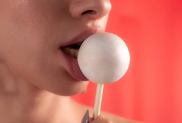 Close up of female lips and candy. Girl eating candy on a stick. Beautiful lips.