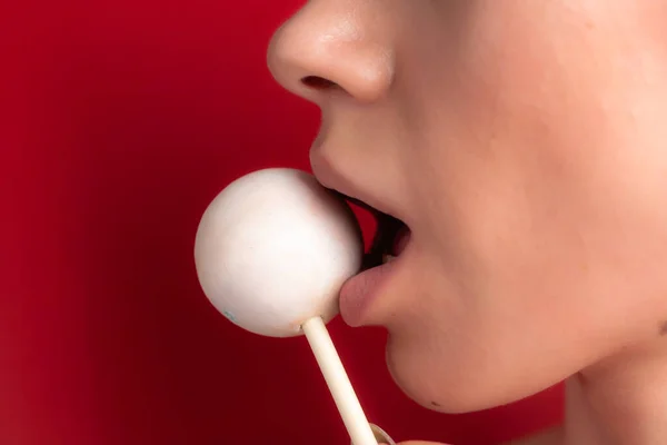 Close up of female lips and candy. Girl eating candy on a stick. Beautiful lips.