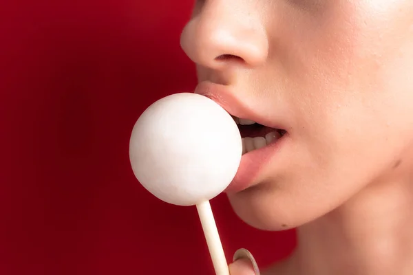 Close up of female lips and candy. Girl eating candy on a stick. Beautiful lips.