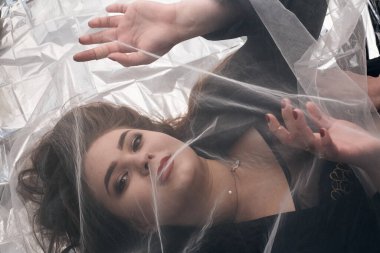 Tombul bir kızın güzel makyajı tül kumaşın altında altın bir folyonun üzerinde yatıyor..