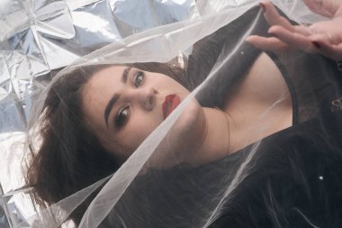 Tombul bir kızın güzel makyajı tül kumaşın altında altın bir folyonun üzerinde yatıyor..