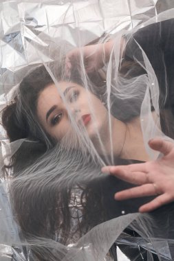 Tombul bir kızın güzel makyajı tül kumaşın altında altın bir folyonun üzerinde yatıyor..