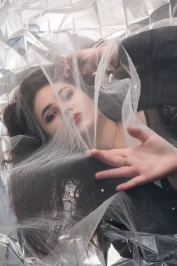 Tombul bir kızın güzel makyajı tül kumaşın altında altın bir folyonun üzerinde yatıyor..