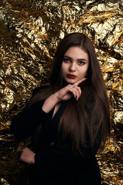 Altın bir arka planda siyah ceketli şık tombul bir kız..