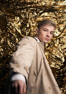 Bej ceketli, altın kaplama beyaz gömlekli şık bir adam..