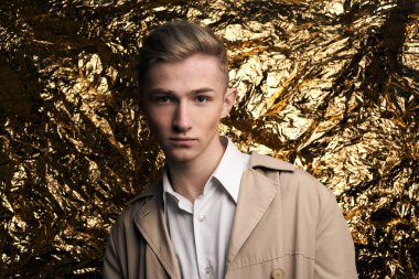 Bej ceketli, altın kaplama beyaz gömlekli şık bir adam..